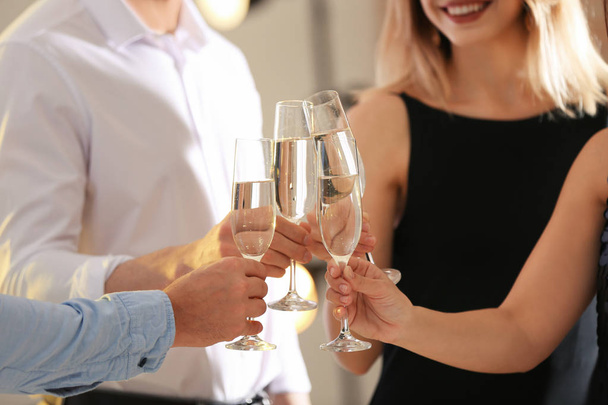 Vrienden rammelende bril met champagne op feestje binnenshuis, close-up - Foto, afbeelding
