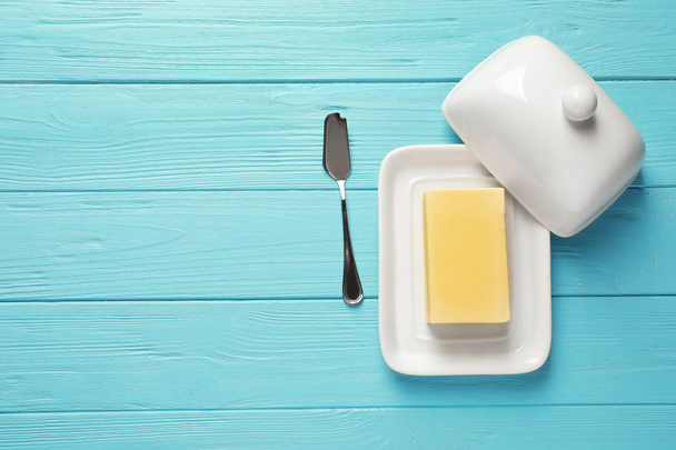 Dish with fresh butter and knife on wooden background, top view. Space for text - Foto, imagen