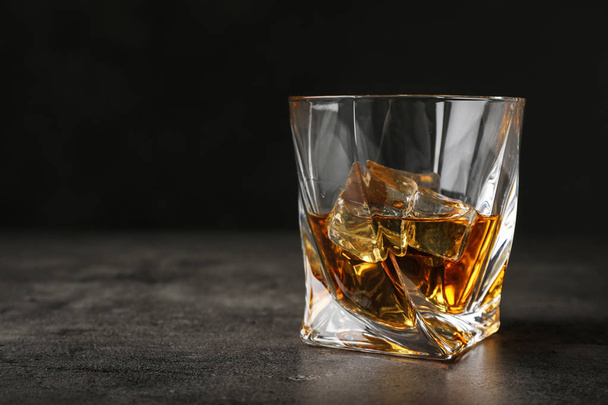 Golden whiskey in glass with ice cubes on table. Space for text - Foto, Bild