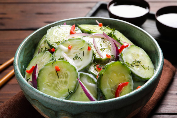 Dish with fresh creamy cucumber salad on wooden table - Zdjęcie, obraz