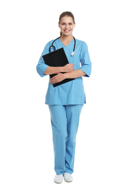 Full length portrait of young medical assistant with stethoscope and clipboard on white background - Фото, изображение