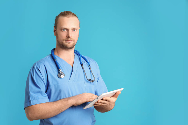 Portrait of medical assistant with stethoscope and tablet on color background. Space for text - Foto, Imagem