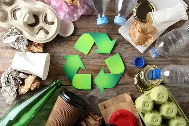 Recycling symbol and different garbage on wooden background, top view - Фото, зображення