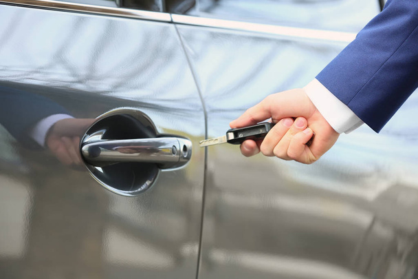 Closeup view of man opening car door with key - Фото, изображение