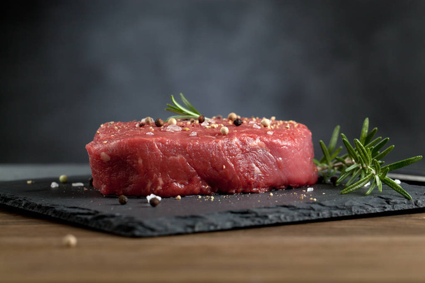 Raw beef steak on a dark wooden table. - 写真・画像