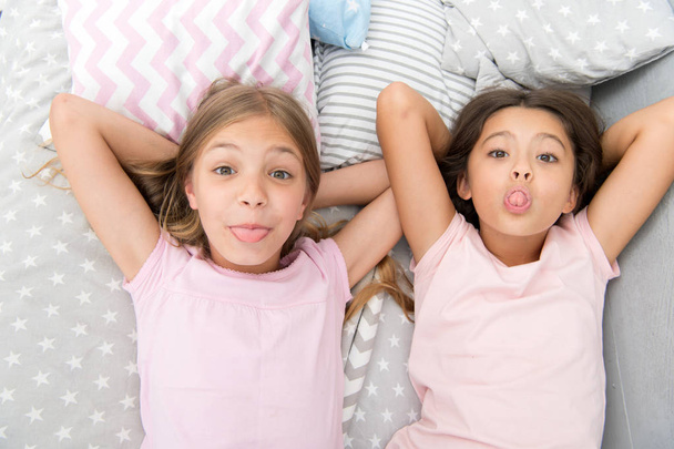 Leisure and fun. Having fun with best friend. Children playful cheerful mood having fun together. Pajama party and friendship. Sisters happy small kids relaxing in bedroom. Friendship of small girls - Фото, изображение