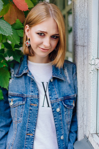 Fashion girl standing outdoors in denim oversized jacket and beautiful ear rings. - Foto, Imagen