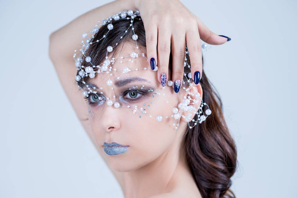 Beautiful model girl with blue manicure nail design,face and hair with beads, rhinestones ,decoration. Fashion makeup and care for hands and nails and cosmetics.Nail art design.emale beauty. Luxury - Фото, изображение