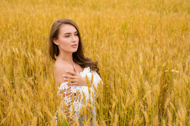 Portrait of a young sexy blonde woman on a background of golden wheat field, summer outdoors - 写真・画像