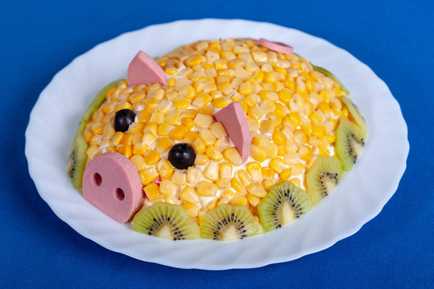 Veldsla in de stijl van het nieuwe jaar-het jaar van het gele varken. Symbool van de nieuwe 2019 op de Chinese horoscoop. Feestelijke maaltijd. Salade in de vorm van een hartje op een blauwe achtergrond. - Foto, afbeelding
