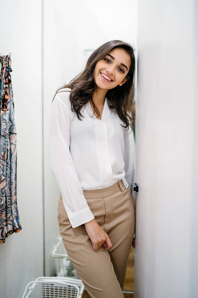 Portrait of a young and beautiful Indian Asian woman trying out new clothing in a fitting room in a fashion shop in a mall. - Foto, Imagem