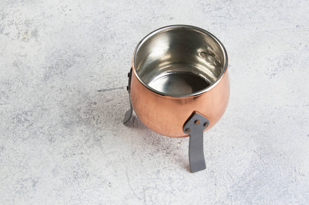 Vintage footed copper pot on concrete background. Copy space for text. - Foto, afbeelding