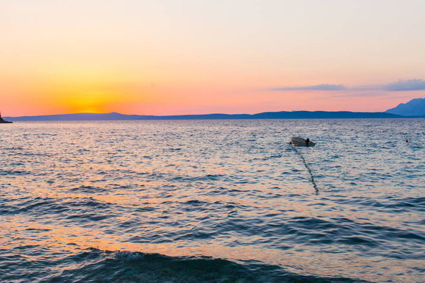 Beautiful sunset on the sea with small boat - 写真・画像