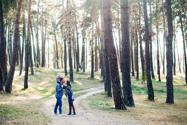 A cute family - mom, dad and son spend fun time outdoors in a beautiful pine forest. - Photo, Image