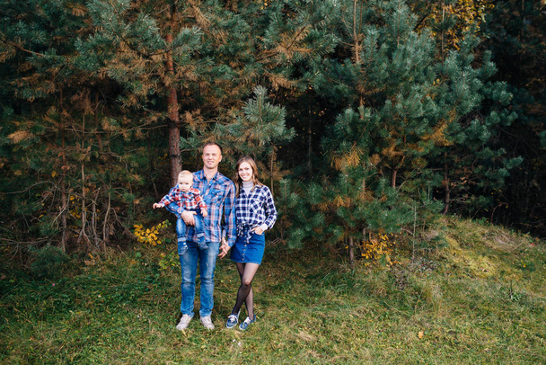 Uma família fofa mãe, pai e filho passam tempo divertido ao ar livre em uma bela floresta de pinheiros
. - Foto, Imagem