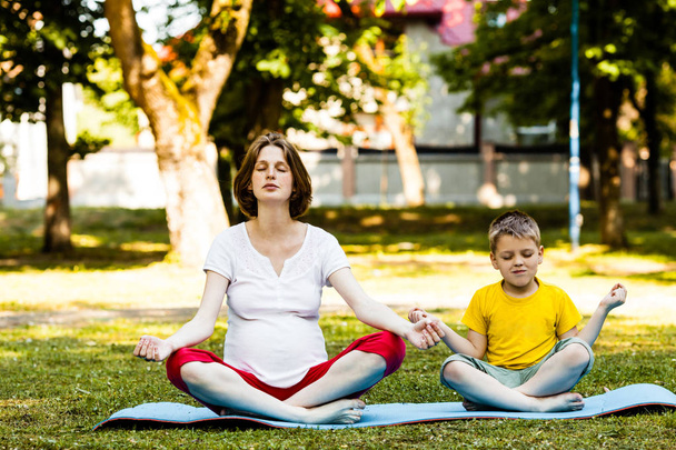 Future mom relaxing while yoga class outdoor in the summer - Foto, afbeelding