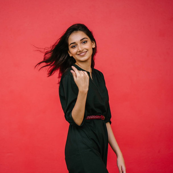 Studio portrait of a beautiful, young and attractive Indian Asian woman against a red studio background. She is elegantly dressed - Foto, immagini