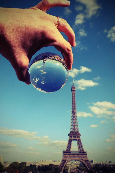 hand of tourist with a big glass sphere and the Eiffel Tower in Paris France with vintage old effect - Photo, Image