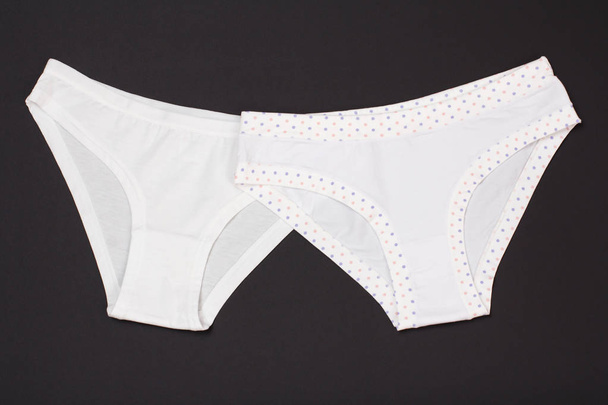 Beautiful white cotton panties on black background. Woman underwear set. Top view. - Photo, Image