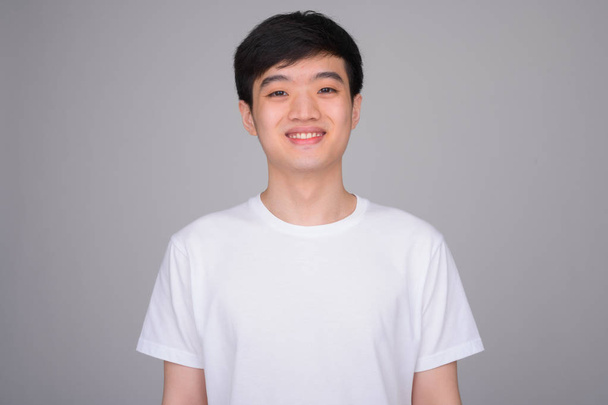 スタジオショットの若い幸せなアジアの男の笑顔 - 写真・画像