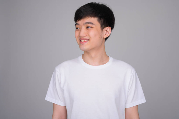 Studio ampui nuorta onnellista aasialaista miestä hymyillen ajattelemalla
 - Valokuva, kuva