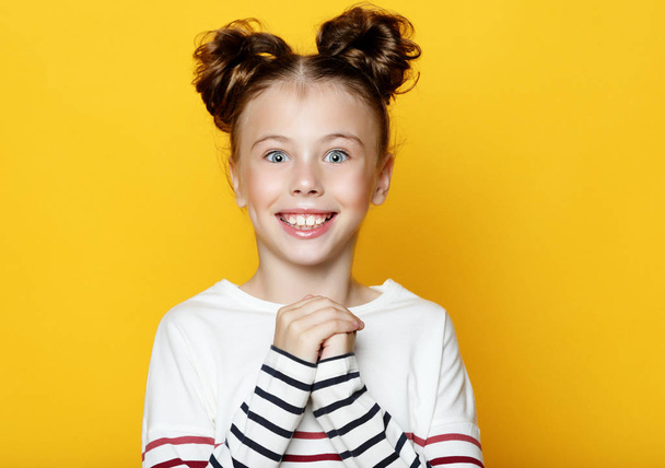 Portrait of cheerful smiling little girl on yellow background  - Фото, изображение