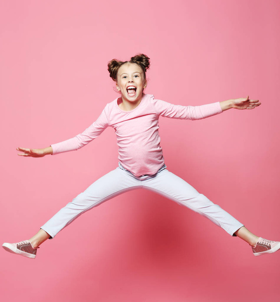  funny child girl dressed casual jumping on pink  background  - Foto, Imagem