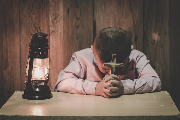 Junge Hände halten ein heiliges Kreuz und beten zu Gott, Kind betet für Gott Religion. - Foto, Bild