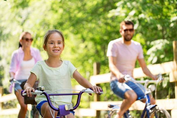 happy family riding bicycles in summer park - Photo, Image