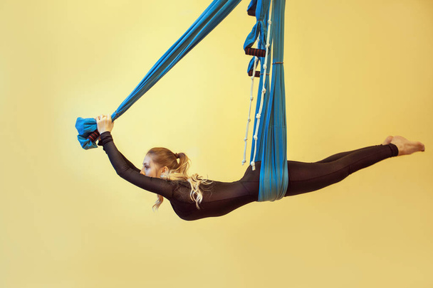beautiful flexible woman doing yoga poses on yellow background - Fotoğraf, Görsel