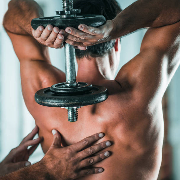 Entraîneur permanent avec client masculin faisant de l'exercice dans la salle de gym
 - Photo, image