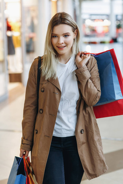 Young happy woman smile and walk in big city shopping mall and find good price and discount in store. Concept: shopping, sales, Consumerism, lifestyle - Valokuva, kuva