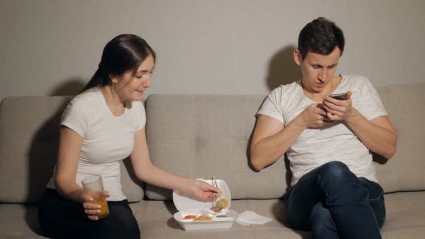 Kobieta się nudzić podczas człowiek przy play na telefonie komórkowym w domu - Materiał filmowy, wideo