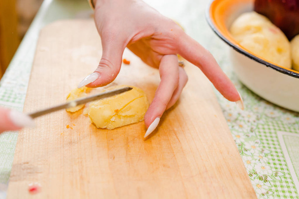 The woman cuts vegetables on salad. Cuts potatoes, beet, carrots. - Foto, immagini