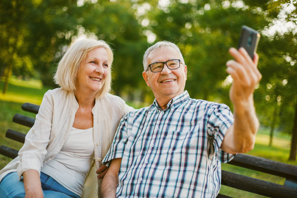 heureux senior couple prend selfie dans parc
.  - Photo, image