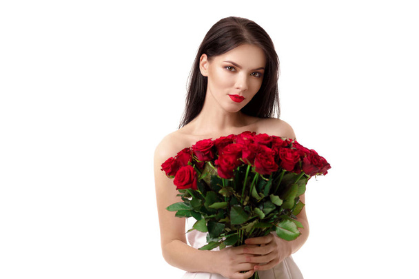 beautiful young woman with a large bouquet of red roses - Фото, зображення
