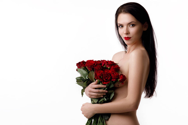 beautiful young woman with a large bouquet of red roses - 写真・画像