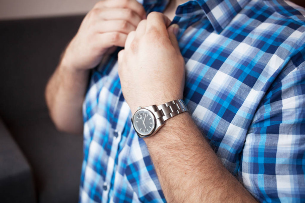 sturdy man in a blue plaid shirt with a short sleeve and a watch on his wrist buttons collar - Foto, Imagem