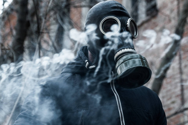 Homem com máscara de gás contra fundo de desastre. Conceito de poluição
 - Foto, Imagem