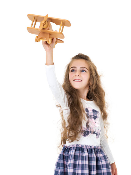 La bambina sta giocando con un aereo di legno. - Foto, immagini