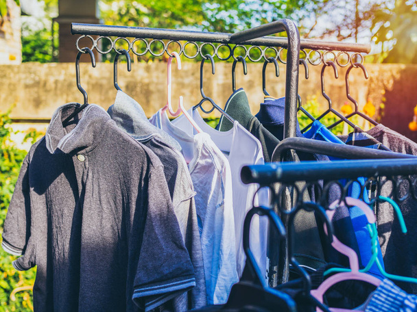 Vele kleuren shirts op hanger zijn opknoping op de waslijn met zon. - Foto, afbeelding