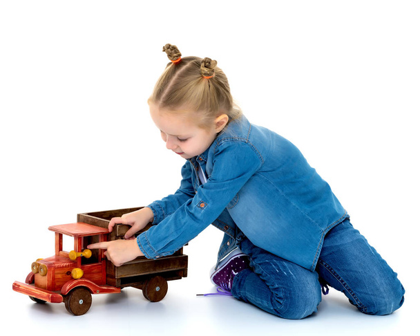 Little girl is playing with a wooden car. - 写真・画像
