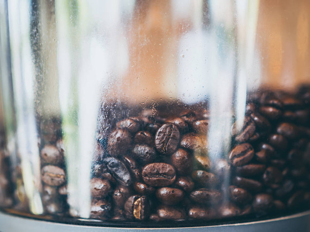 電動コーヒーミルでコーヒー豆を閉じます。コーヒー豆のテクスチャ背景. - 写真・画像