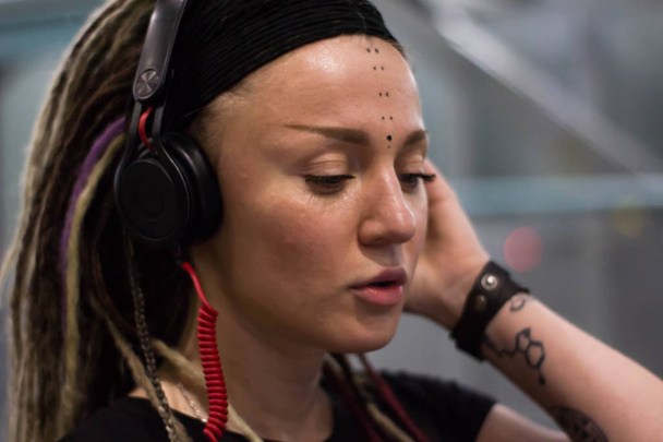 mujer joven con rastas en auriculares escuchando música y bailando en el aeropuerto por la noche. divertirse
 - Foto, Imagen
