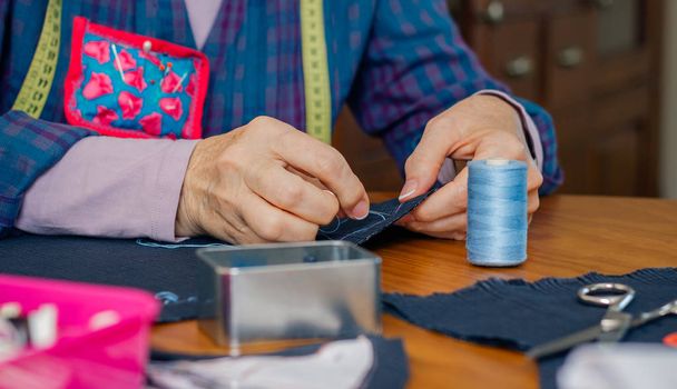 Senior female seamstress sewing cloth - Photo, Image