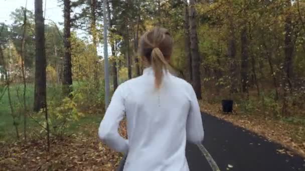 Młoda Blondynka kobieta działa w parku jesień. - Materiał filmowy, wideo
