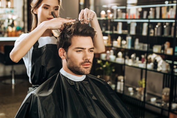 beautiful young hairdresser cutting hair to handsome man in beauty salon - Foto, Imagem