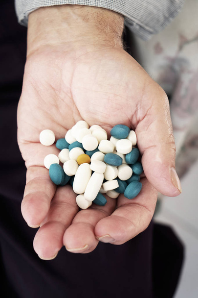 Close-up van een senior blanke man met een stapel van verschillende pillen in zijn hand - Foto, afbeelding