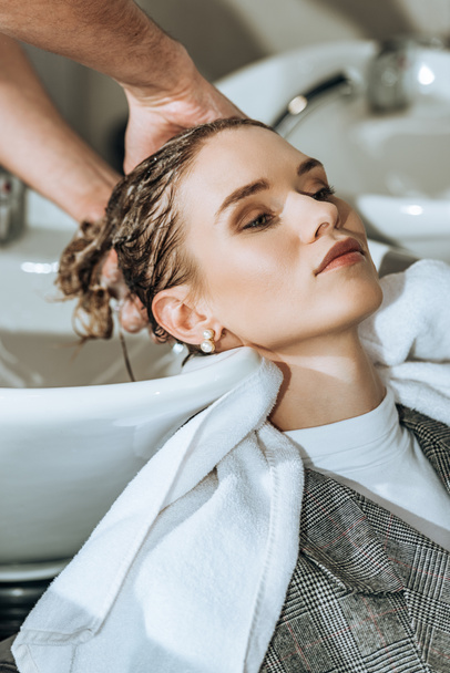 частичный вид крупным планом парикмахера, моющего волосы привлекательной девушке в салоне красоты
   - Фото, изображение