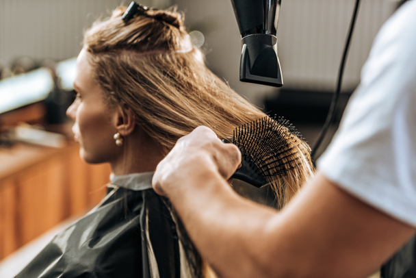 cropped shot of hairdresser drying hair to attractive girl in beauty salon   - Foto, Imagen